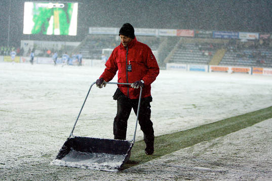 En vaktmästare skottar fram sidlinjerna som snön har