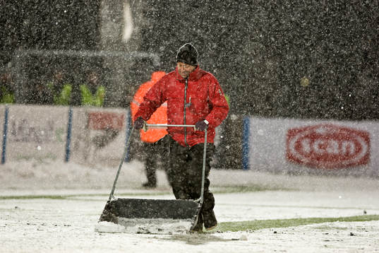 En vaktmästare skottar fram sidlinjerna som snön har