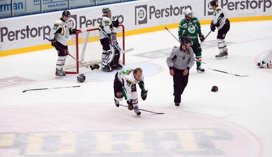 Slagfält, som NHL, handskar och klubbor ligger utspridda.