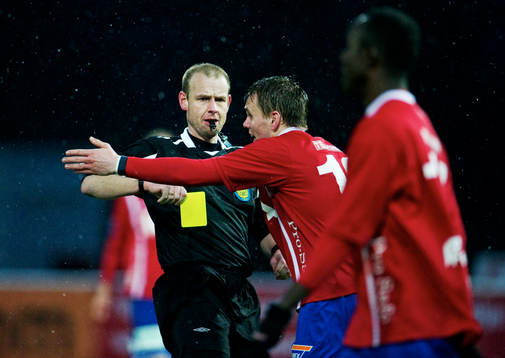 Fredrik Lundberg, domare, delar ut ett gult kort