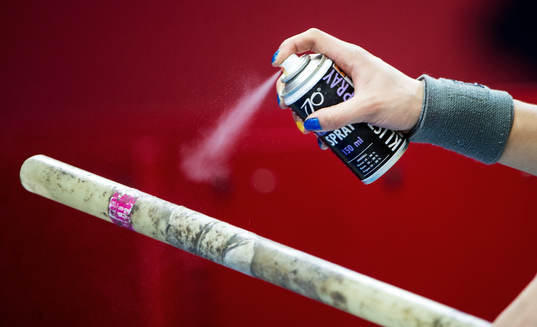Stavhoppare sprayar lim på staven innan hoppet