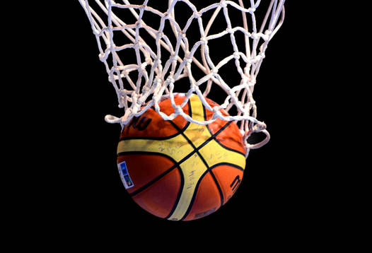 En basketkoll faller genom nätet i en basketkorg i matchen