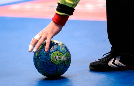 En målvakt plockar upp en handboll