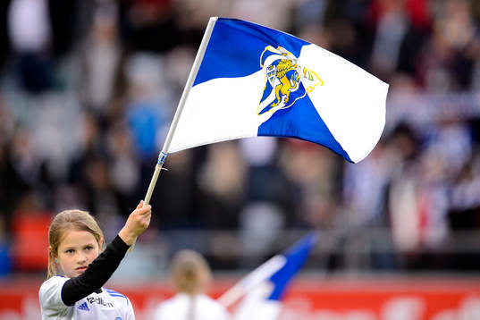 En tjej viftar med en flagga innan fotbollsmatchen i