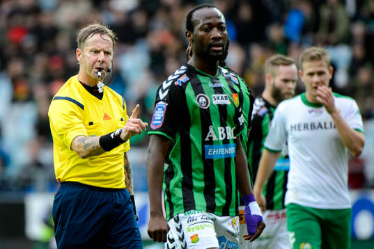 Domare Lars Olsson blåser i pipan och gestikulerar