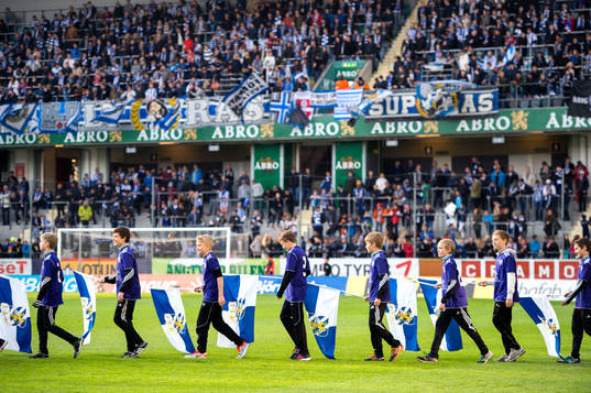 Flaggbärare gå in på planen innan en fotbollsmatch i
