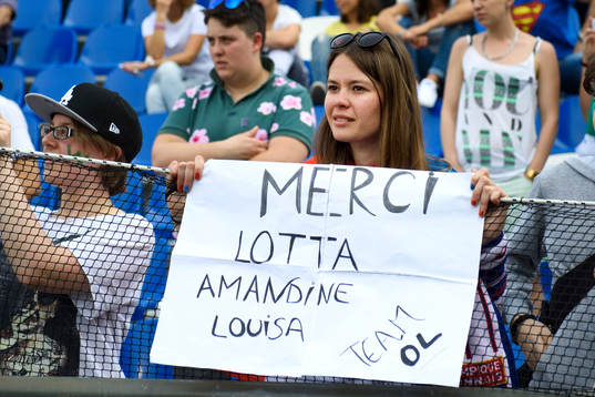 En supporter håller en skylt med texten "Merci Lotta