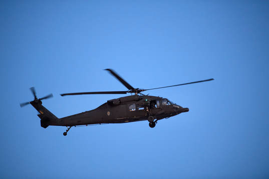 En militärhelikopter flyger över planen på en träning