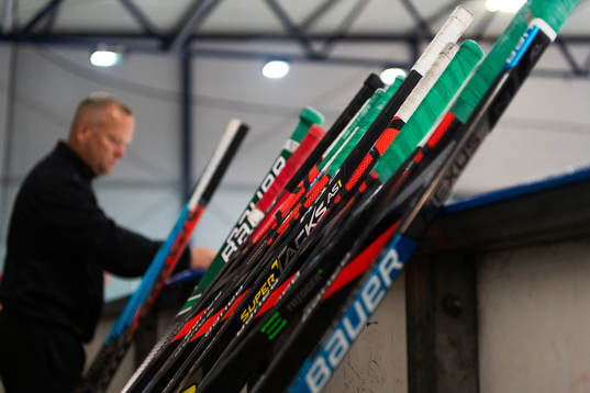 Ishockeyklubbor står lutade mot sargen på en träning med