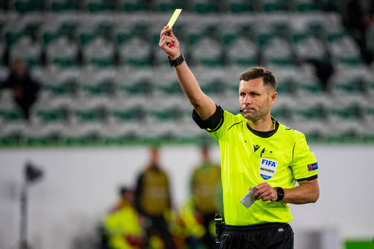 Referee Gediminas Mažeika gives a yellow card