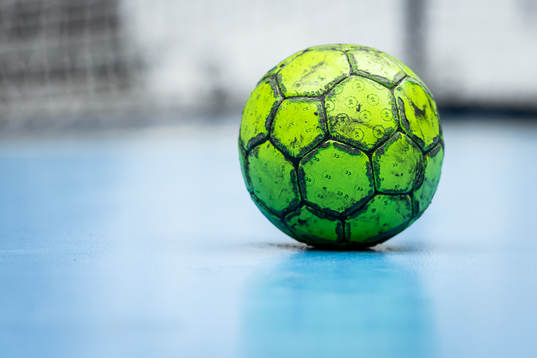 En grön handboll ligger på spelplanen