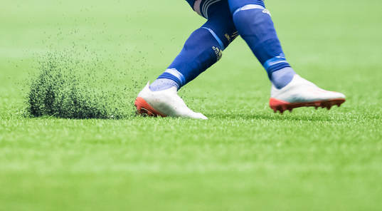 Fotbollsspelare sparkar upp granulat