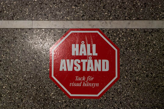 En klisterlapp på golvet som uppmanar att hålla avstånd