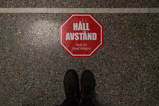 En klisterlapp på golvet som uppmanar att hålla avstånd