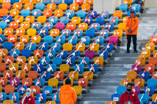 Stewards stand midst the empty seats in the stands