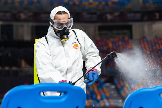 A person in protective gear disinfects chairs at the