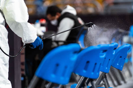 A person in protective gear disinfects chairs at the