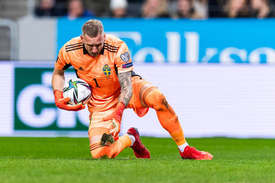 Goalkeeper Robin Olsen of Sweden throws a patch of grass