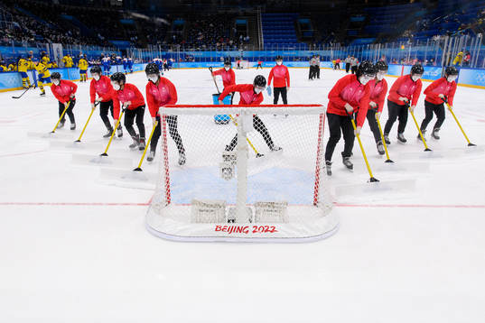 Volunteers clean the ice in the men's ice hockey bronze