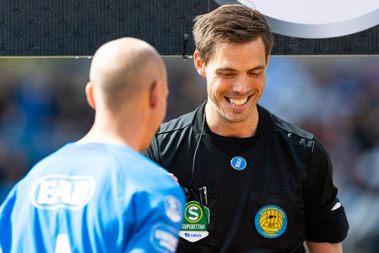 Domare Magnus Lindgren singlar slant före fotbollsmatchen