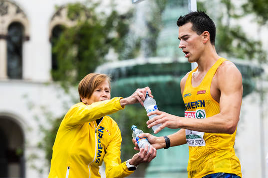 Mother and coach Siv Karlström hands over water  to