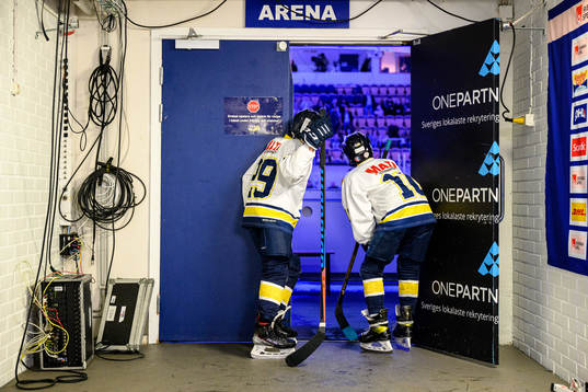 Ett par juniorspelare står och tittar in i arenan innan