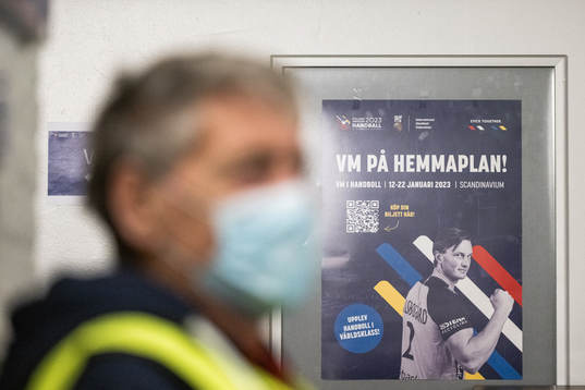 A volunteer with a face mask is seen in the foreground of a