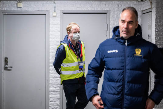 A volunteer with a face mask watch as goalkeeper coach