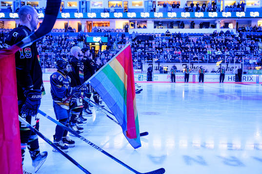 Juniorer håller prideflaggor vid lineup innan