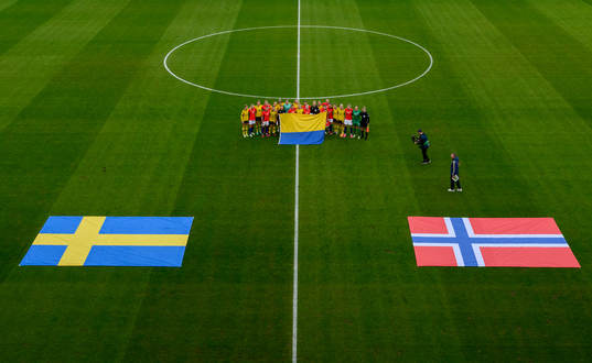 The players of Sweden and Norway hold the Ukranian flag at