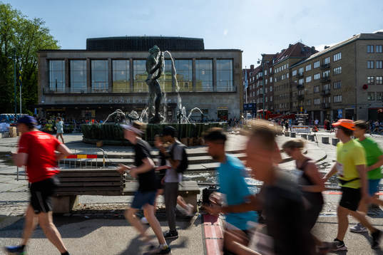 Löpare springer förbi statyn Poseidon