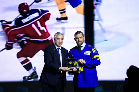 Luc Tardif, president of the IIHF, hands over a trophy to