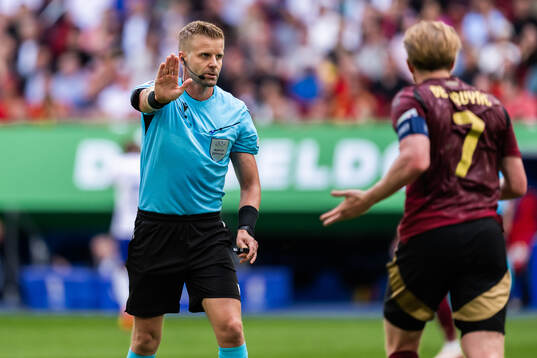 Referee Glenn Nyberg and Kevin De Bruyne of Belgium