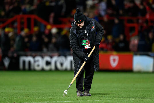 A steward repairs the pitch at halftime