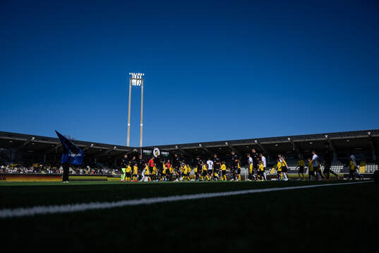 Häckens och Mjällbys spelare går in på plan
