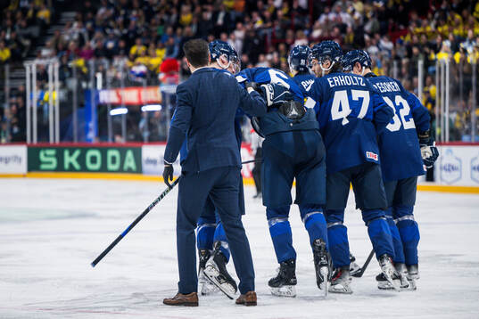 Tony Sund of Finland is helped off the ice by Eemil Erholtz