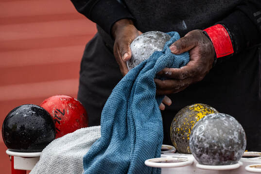 An athlete dries the shot with a towel